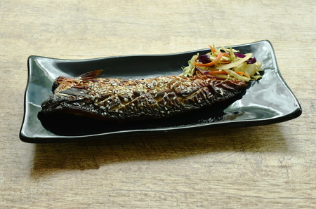 grilled Saba fish or mackerel with sweet black soy sauce topping white sesame on plate