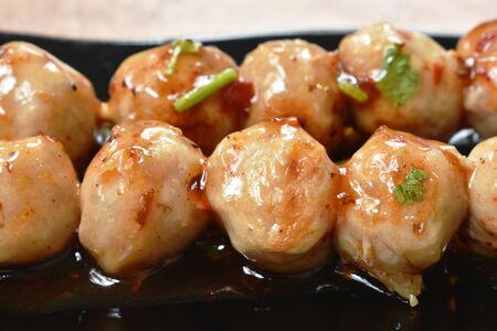 grilled pork tendon meat ball stabbing in wooden stick dressing spicy and sweet sauce on plate