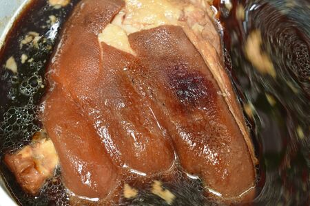 braised pork leg with black Chinese herb soup boiling in cooking pot