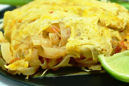Pad Thai stir fried rice noodles with dry shrimp wrapped with egg on plateの写真素材