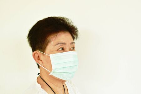 Asian elder woman wearing hygienic mask robe for protection nose and mouth from virusの写真素材