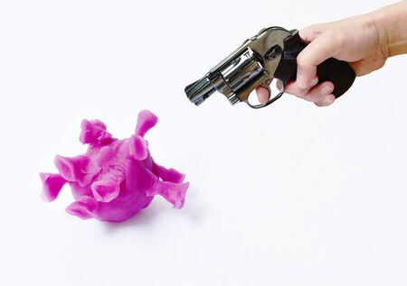 hand holding revolver gun prepare to shoot purple coronavirus or COVID-19 sculpture by clay on white backgroundの写真素材
