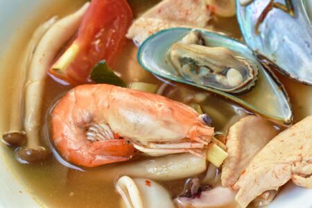 boiled shrimp and chicken with mussel in Thai spicy tom yum soup on bowlの写真素材