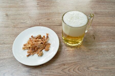 baked dry salty squid slice on plate eat couple with cold beer on tableの写真素材