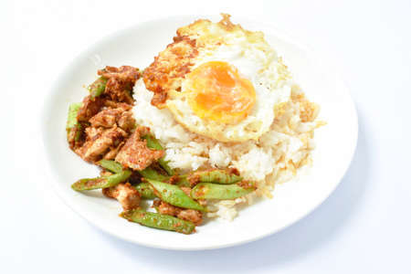 spicy fried pork with slice yard long bean in curry on rice topping eggの写真素材