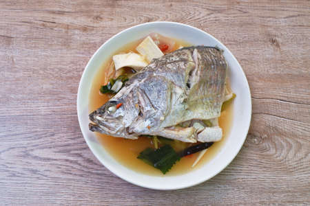 spicy bass fish head and slice coconut shoot in Tom Yum soup on plateの写真素材
