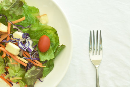 fresh vegetable salad topping crispy bread dressing on plate with silver forkの写真素材