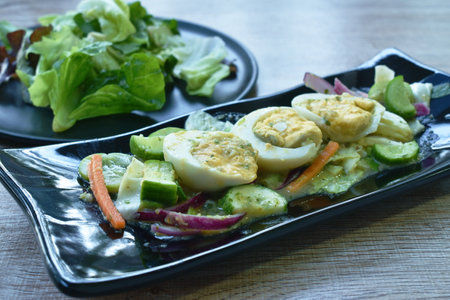 boiled egg half cutting tin sour and spicy salad on plate with fresh vegetableの写真素材