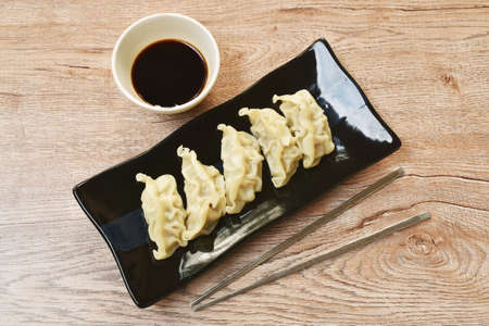 steamed Gyoza or Japanese dumpling stuffed minced pork dipping shoyu sauce on plateの写真素材