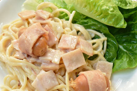 spaghetti carbonara  topping slice ham pork and fresh cos lettuce vegetable on plateの写真素材