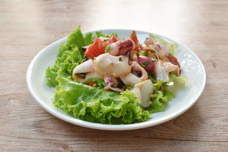 Thai spicy squid salad and fresh vegetable on plateの写真素材