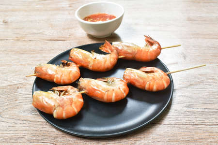 grilled shrimp with salt stabbing wooden stick on plate dipping spicy chili sauceの写真素材