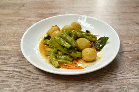 spicy fried fish ball with slice yard long bean in curry sauce on dish