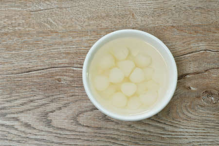 pickled single garlic with salt water in cup on tableの写真素材