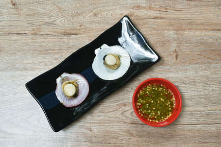 grilled scallops with salt on plate dipping with Thai spicy seafood sauceの写真素材