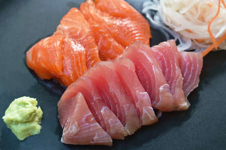 slice raw tuna and salmon fish sashimi Japanese food with radish on plate dipping shoyu or soybean...