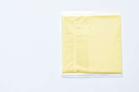 square cheese in clear plastic packing on white backgroundの写真素材