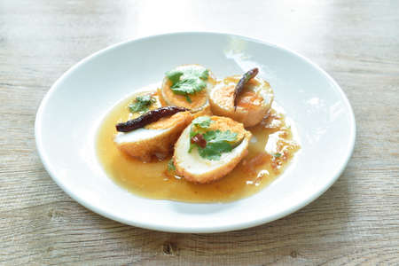 fried egg half cut dressing sweet tamarind sauce topping chili on plate