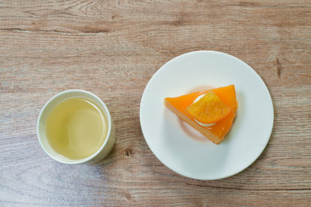 orange cake with cream topping fruit and hot tea cup on tableの写真素材