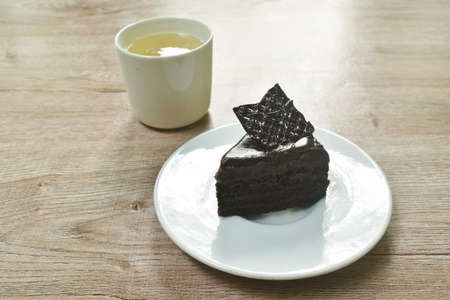 black forest cake with cream topping chocolate and hot tea cup on tableの写真素材