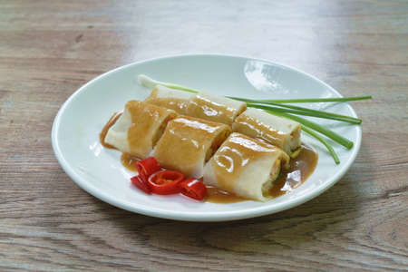 fresh Chinese spring roll made from flour wrapped tofu and pork with bean sprout dressing sweet red gravy sauce on plateの写真素材