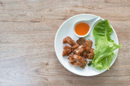 fried fermenting pork bone with garlic dipping chili sauce and fresh vegetable on plate