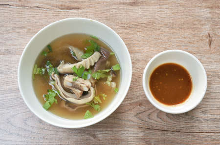 boiled slice pork stomach and bone soup in bowl dipping spicy sauce cup on tableの写真素材
