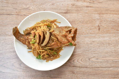 batter fried red grouper fish dressing ginger with mushroom in soy sauce on plate