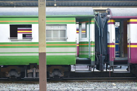 green train parking behind pole in railway station platformの写真素材