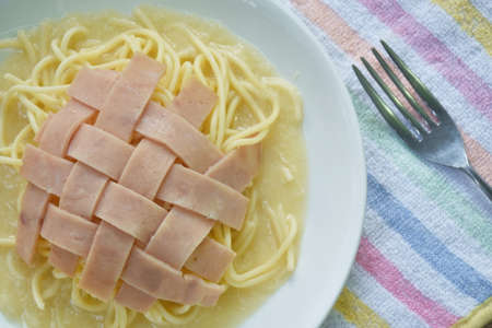 spaghetti white cream sauce topping slice ham pork on plate