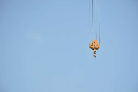 yellow hook of heavy crane for construction building hanging in sky backgroundの写真素材