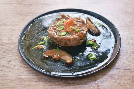 steamed chop pork topping salty egg yolk with mushroom in gravy sauce on plateの写真素材