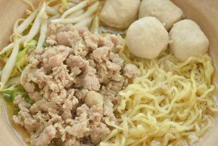 Chinese egg yellow noodles topping boiled chop pork and ball in soup on bowl