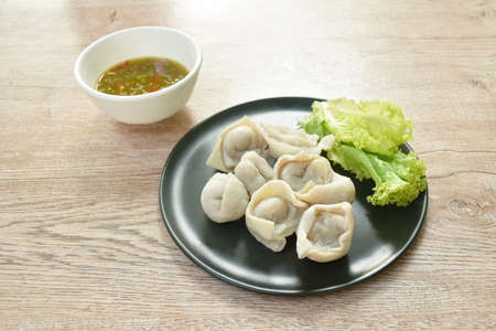steamed fish dumpling with lettuce on plate dipping spicy and sour sauceの写真素材