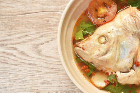 boiled red tilapia fish wit tomato and herb in tom yum soup on bowl