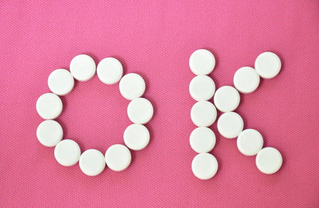 white tablet medicine arranging OK symbol on pink backgroundの写真素材