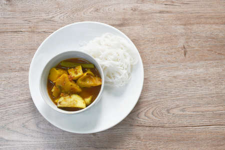 boiled spicy mackerel fish entrails with vegetable curry soup Thai southern style food and rice noodles on plateの写真素材