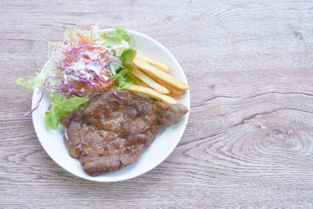 grilled black pepper pork steak with french fries and salad dressing mayonnaise on plateの写真素材