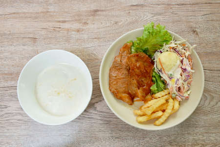 grilled pork steak dressing barbecue sauce with mashed potato and salad on plate couple corn soup in...