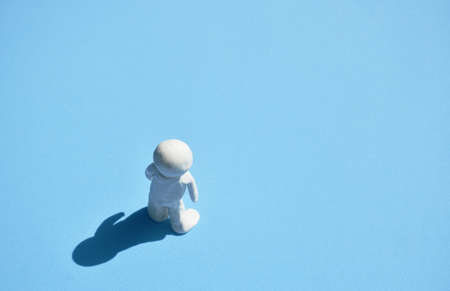 white clay man standing on sunlight with shadow on blue backgroundの写真素材