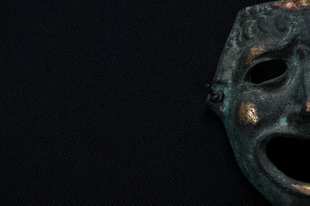 iron human face mask smiling on black fabric backgroundの写真素材