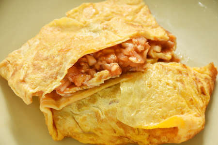 fried mashed pork with tomato and onion stuffed in Thai egg omelets on dishの写真素材