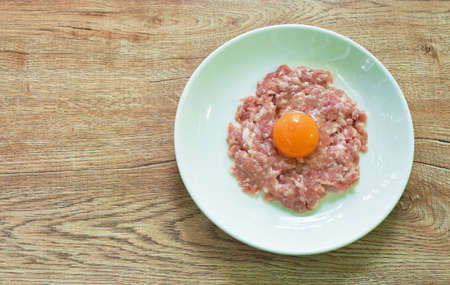 raw mashed pork ingredient food tooping eggg yolk on plateの写真素材