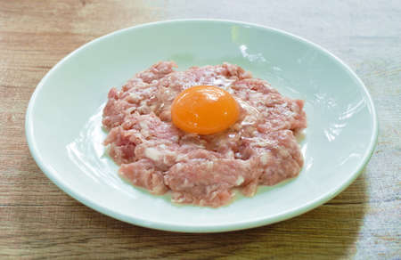 raw mashed pork ingredient food tooping eggg yolk on plate