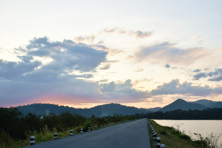 road on water reservoir lake with mountain background in sunsetの写真素材