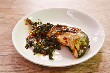 spicy boiled mackerel topping basil in chili sauce on plateの写真素材