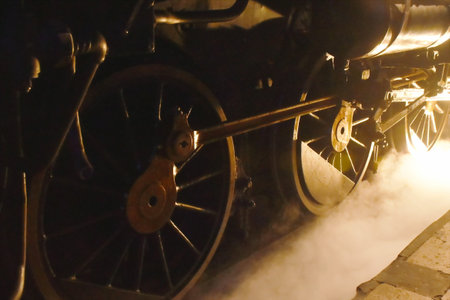 steam locomotive iron wheel with smoke floating on railway in nightの写真素材