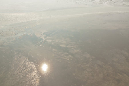 reflection of sun on mud and sand in low tide sea
