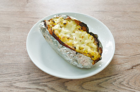 baking Japanese yam stuffing sweet corn seed with cheese in foil on plateの写真素材