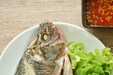 steamed mango fish with lettuce dipping spicy sauce on plateの写真素材
